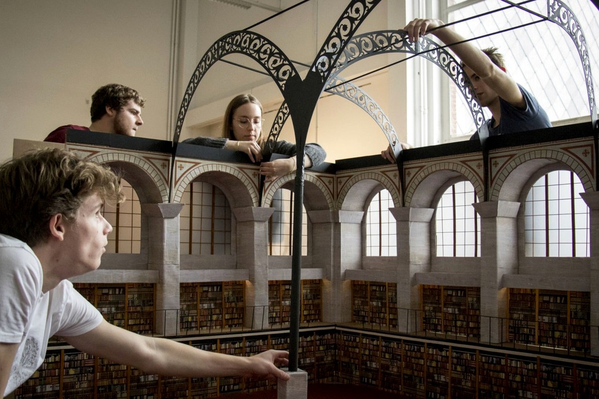 A spacious historic interior with arches, balconies, and visitors.