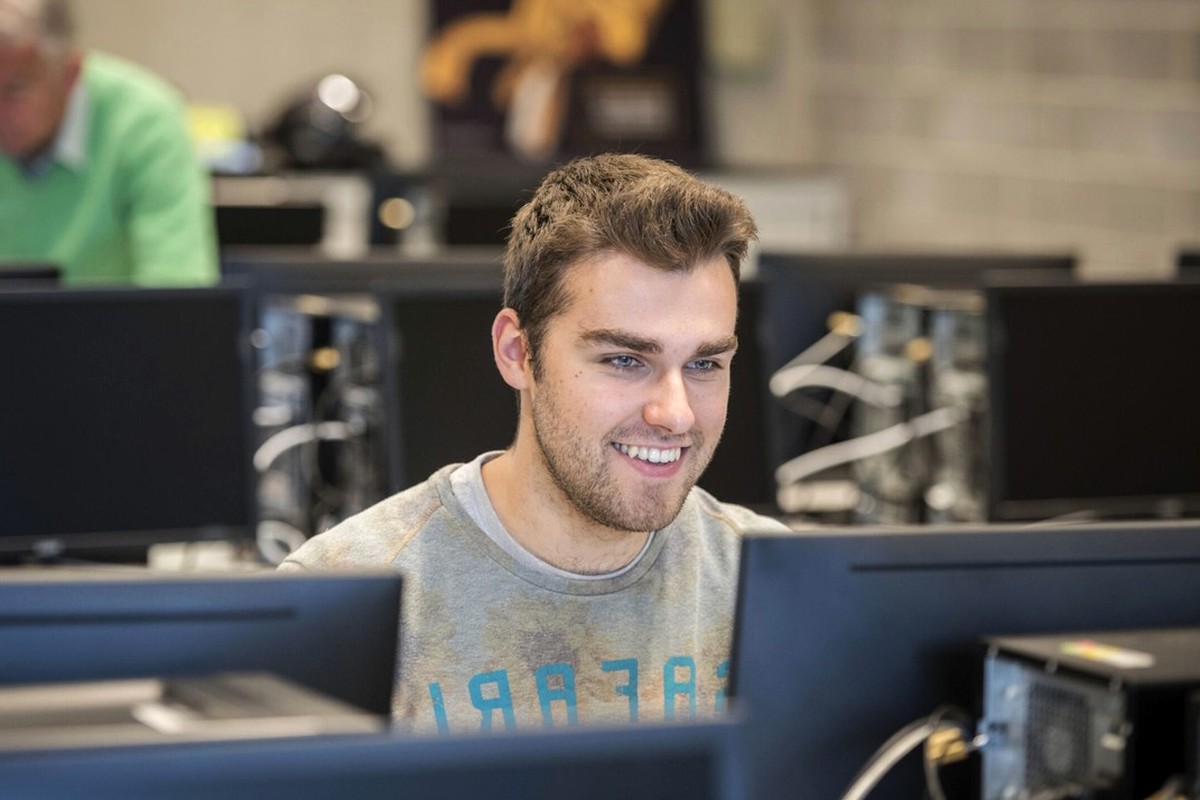 A person working at a desktop computer in a bright indoor workspace.