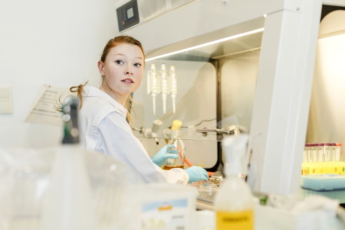 A person working carefully with laboratory equipment in a bright workspace.